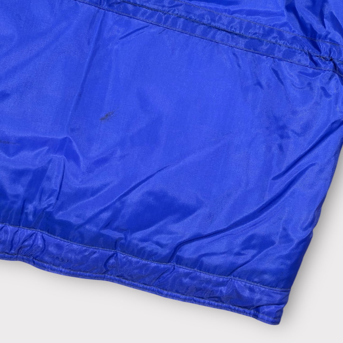 Close-up of a blue jacket with a white background with small mark